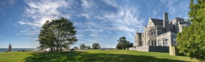 Panoramic view of the Branford Mansion and lawn at UConn's Avery Point campus on a sunny summer day.  The Branford Mansion is a large, gray stone building