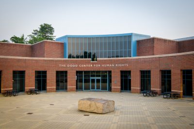 Exterior view of the main entrance to the Dodd Center for Human Rights building.  A large stone sculpture of book is in the foreground of the patio leading to the entrance