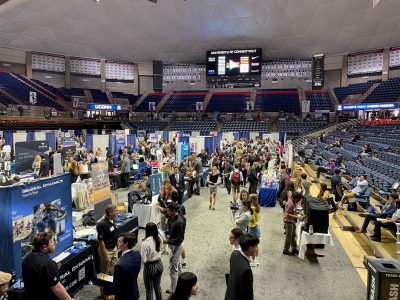 Aerial view of a career fair in Gampel Pavilion. Students are visiting booths and talking with representative from various companies and organizations