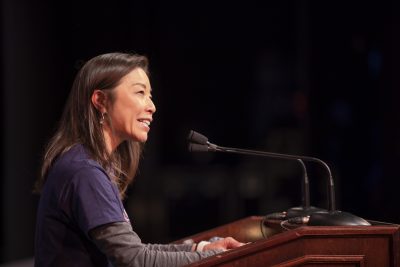 Individual smiling and speaking into microphones at a podium at the 2023 WISH Fest